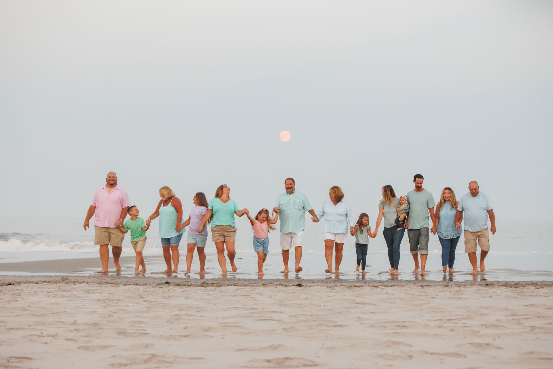Group of people walking hand in hand across a beach at sunset