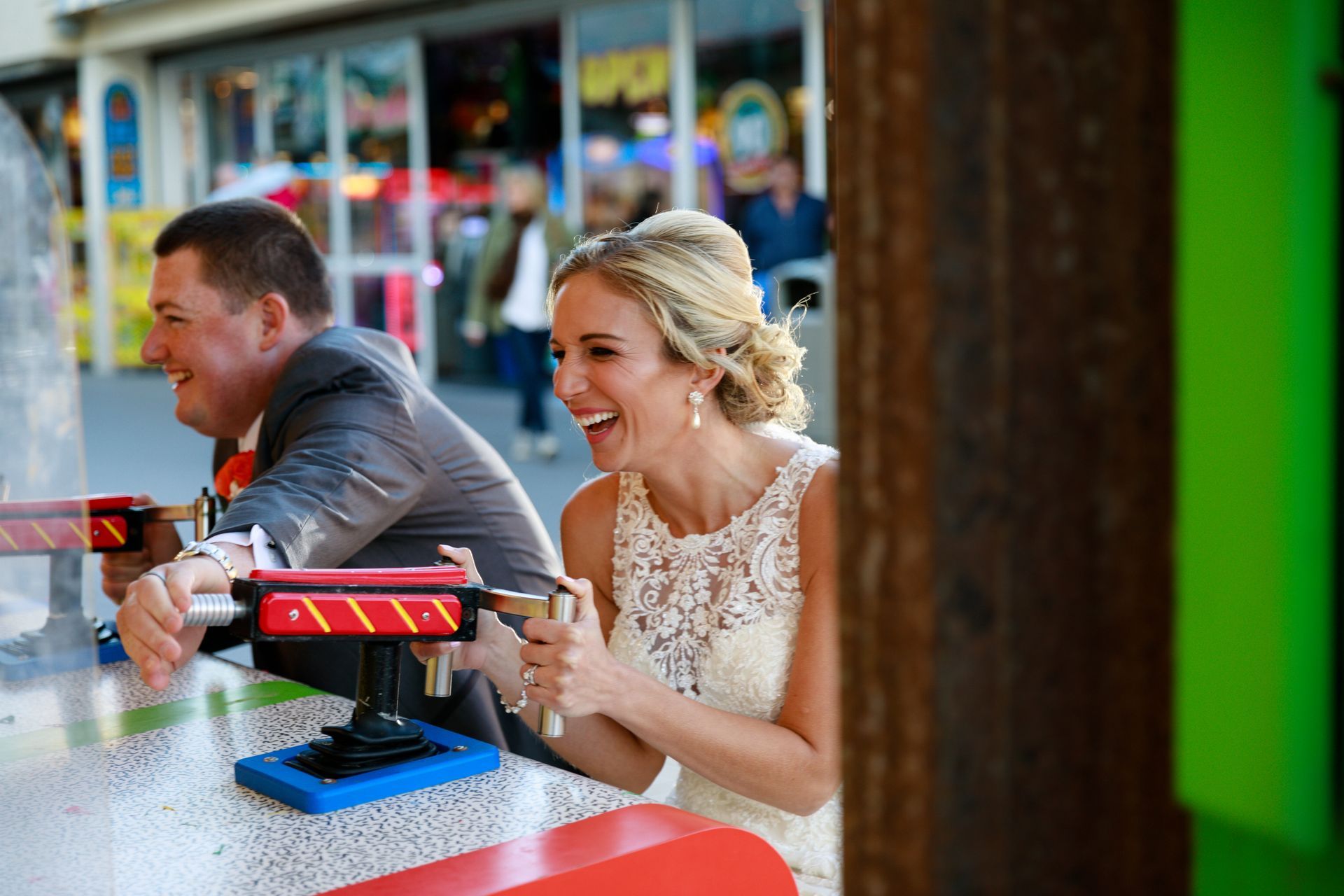 Two people smiling at a carnival game, leaning on a red counter with a blue target in front of them