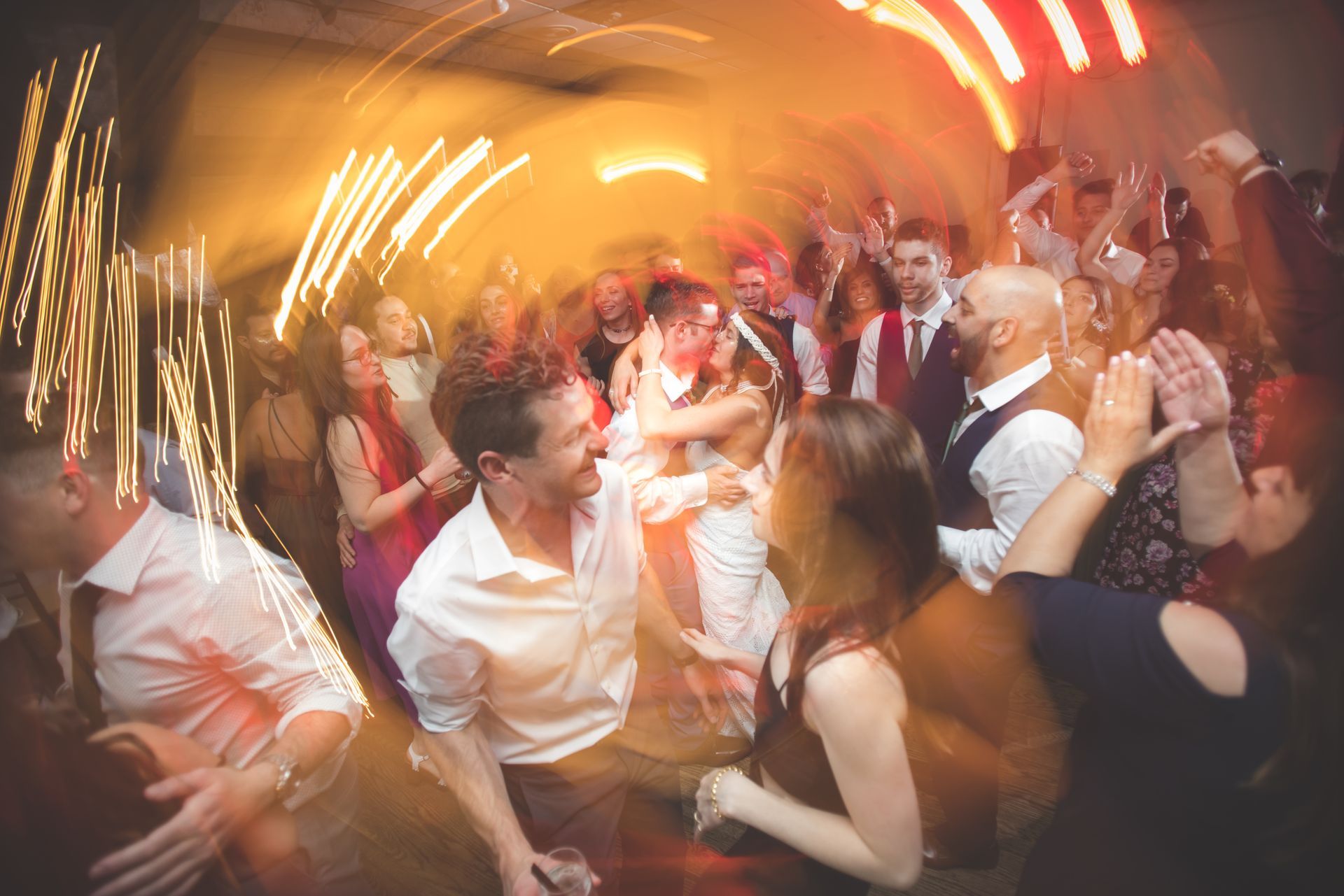 Crowded dance floor with people cheering under warm orange lights and motion blur