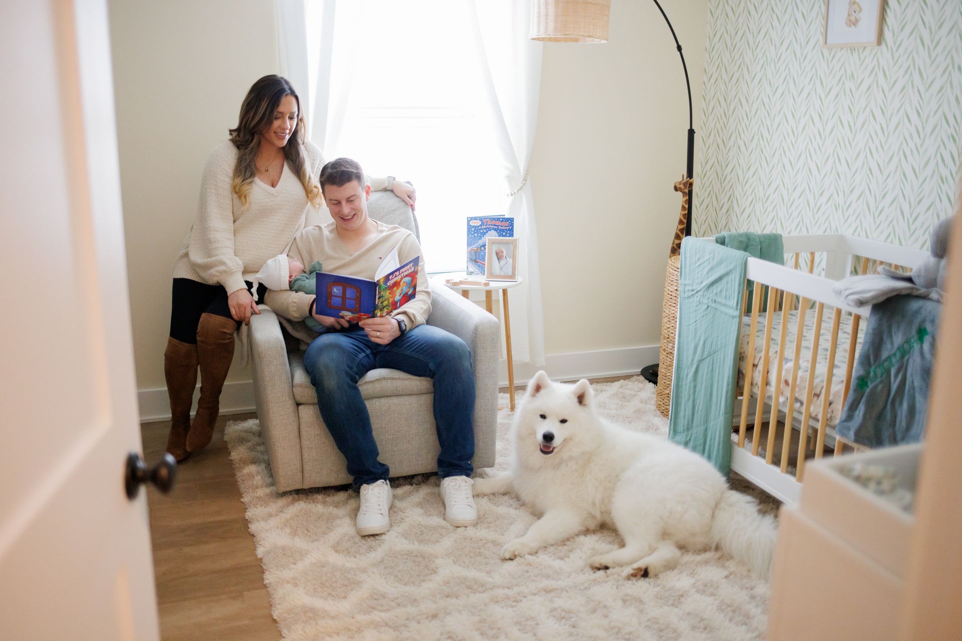 Woman and man reading in a bright nursery, with a white dog resting on the rug.