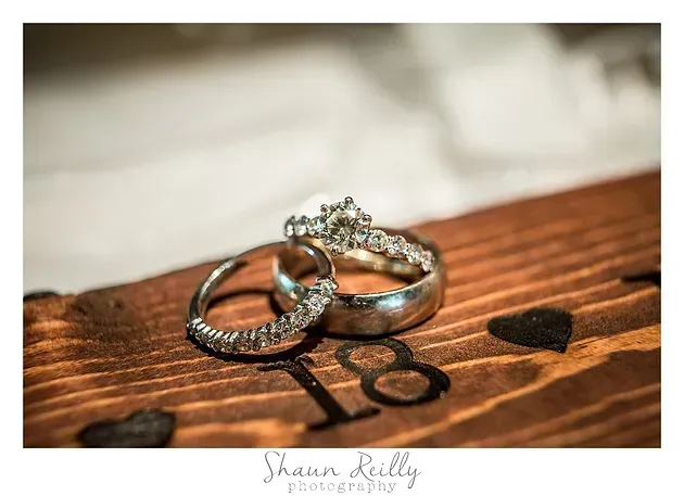 Wedding rings on a wooden surface with the word “love” and a heart cutout.