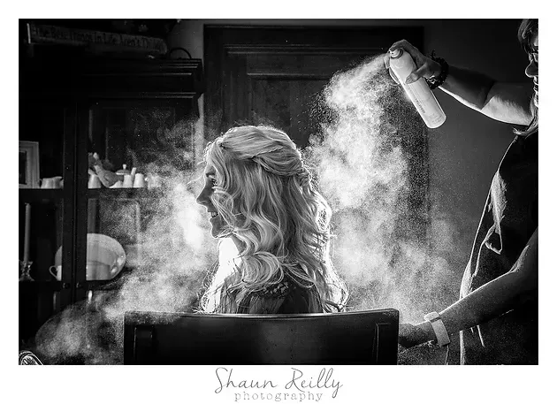 Woman having hair sprayed in a salon, with mist and black-and-white tones