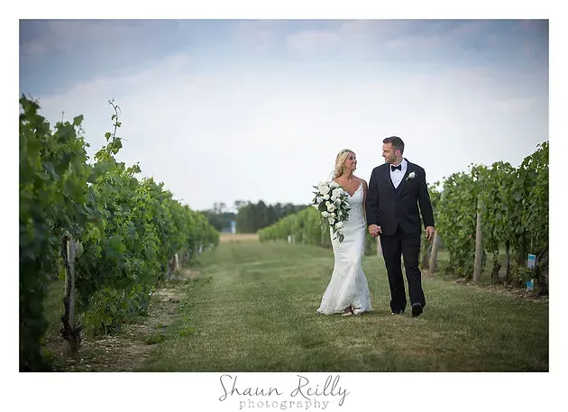 Bride and groom walking hand in hand through a vineyard after the wedding ceremony