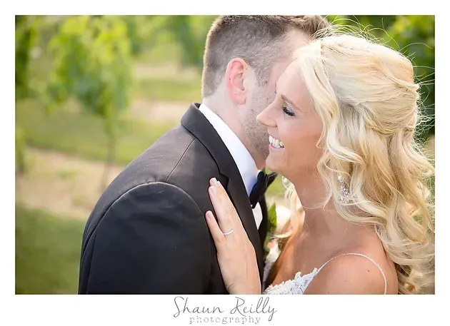 Bride and groom embracing outdoors, smiling in a sunlit garden