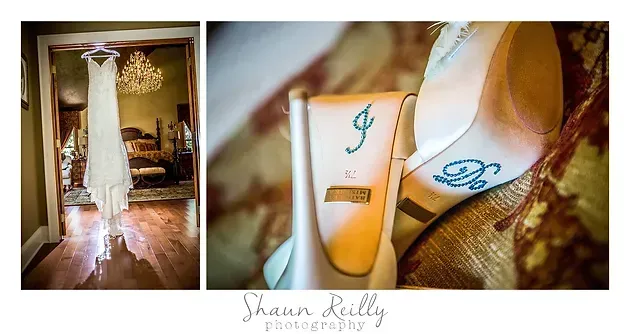 Bridal shoes and matching monogrammed accessories beside a white wedding dress in a softly lit room