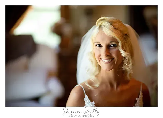 Smiling blonde woman in a white dress at a softly blurred indoor event