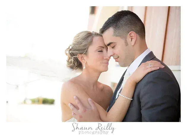 Bride and groom embrace with foreheads touching in a softly lit wedding portrait