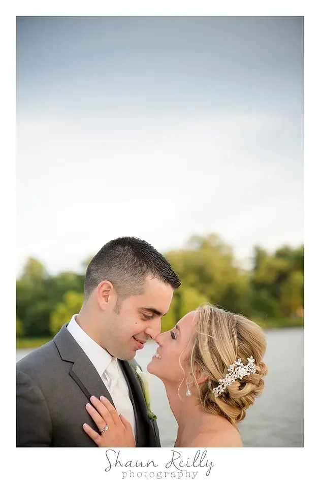 Couple sharing a kiss outdoors, with a soft blurred green background.