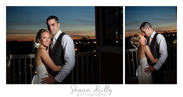 Bride and groom posing at sunset on a balcony, with city lights in the background