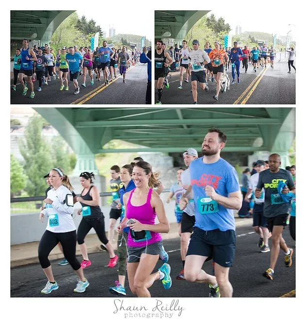 Runners in a road race beneath a green bridge, including a runner in a pink tank top in the foreground