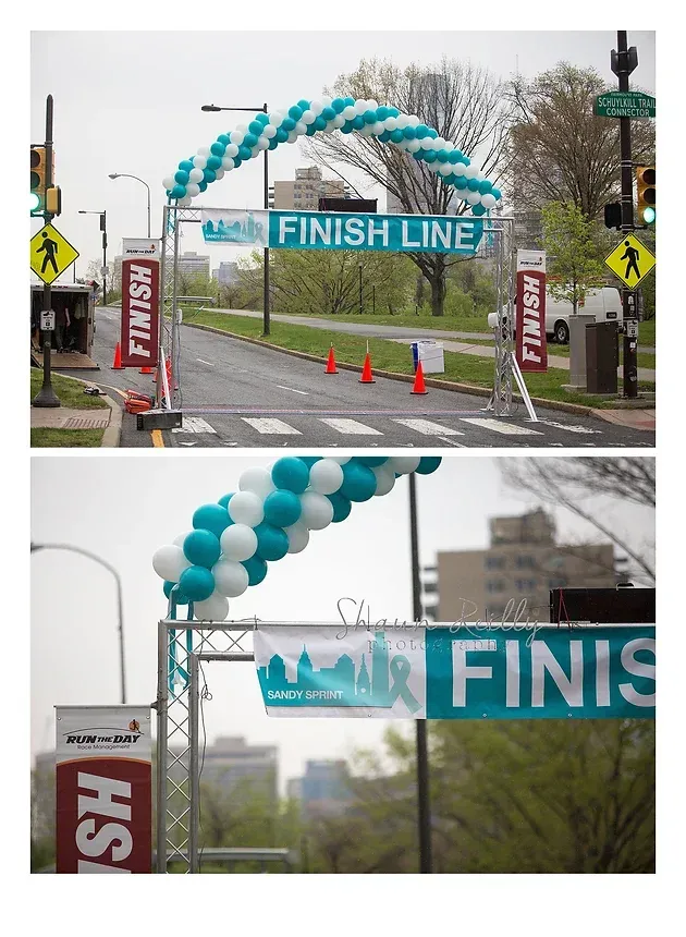 Balloon arch finish line on a street race course, with turquoise and white banners and cones