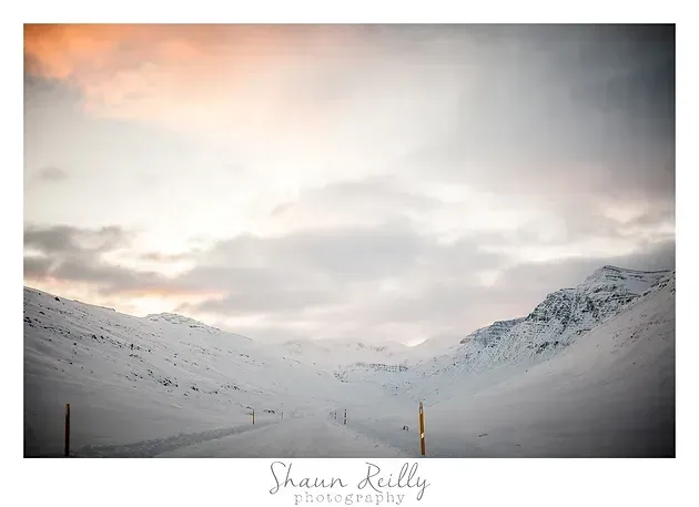 Snowy mountain valley under a pastel sunrise sky