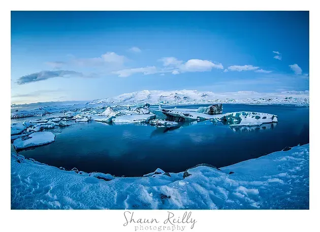 Icy seascape with floating icebergs under a blue sky and calm water