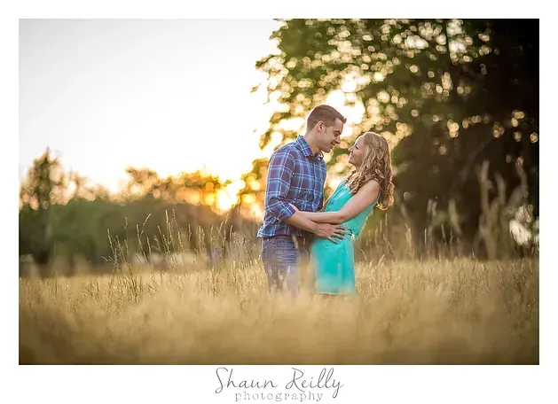 Couple embracing in a sunlit field of tall grass at sunset