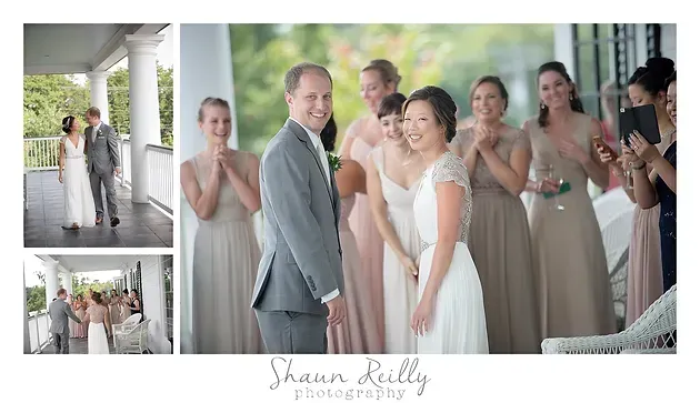 Bride and groom pose with smiling wedding party on white porch in soft daylight