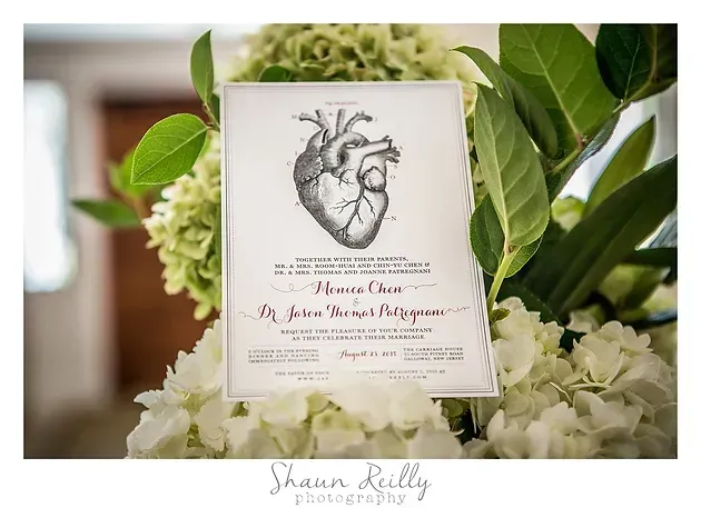 Wedding invitation card with heart illustration among white flowers and green leaves