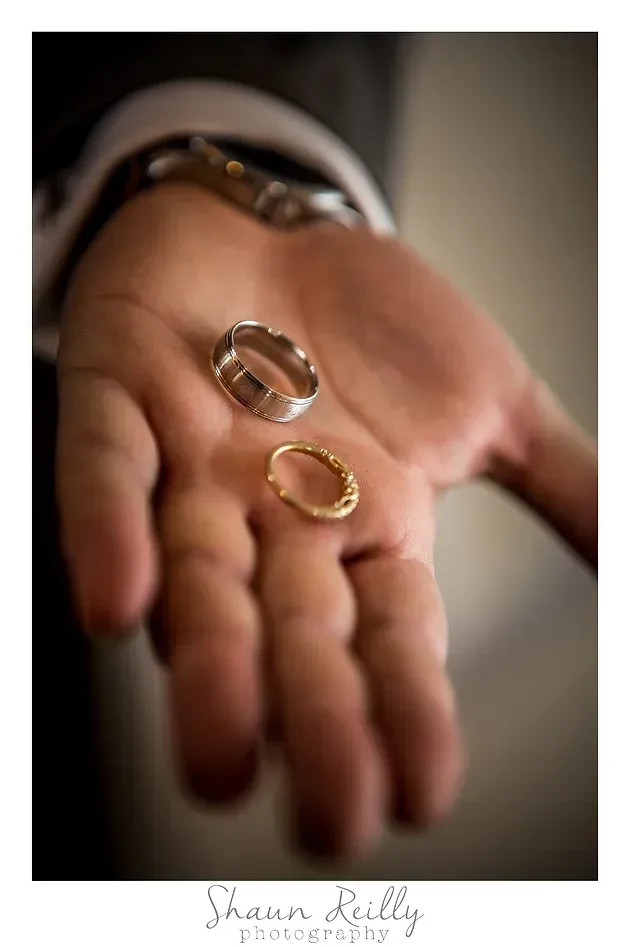 Open palm holding two wedding rings, one silver and one gold, on a soft blurred background
