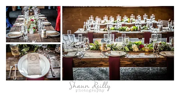 Elegant rustic wedding table setting with white plates, glassware, candles, and greenery on a wooden table.