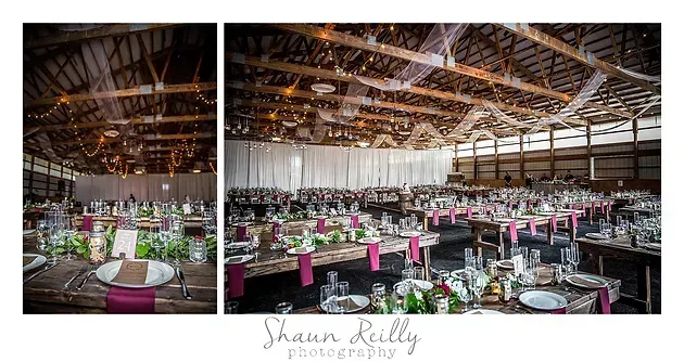Rustic barn wedding reception with round tables, pink accents, and warm string lighting under a wooden ceiling