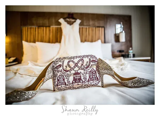 Embellished bridal dress and sash laid out on a bed in a hotel room