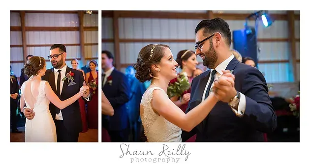 Wedding couple dancing closely in a warmly lit reception hall, with roses and guests in the background