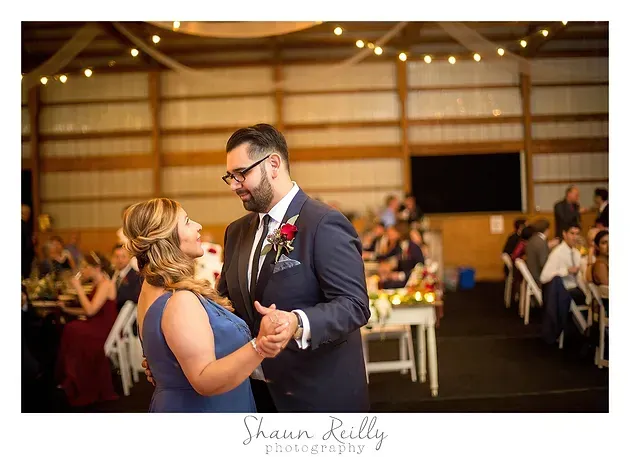Couple dancing at a wedding reception in a warmly lit barn venue