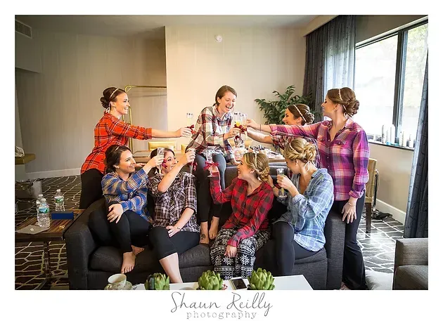Group in plaid shirts posing and laughing together in a bright room near a window