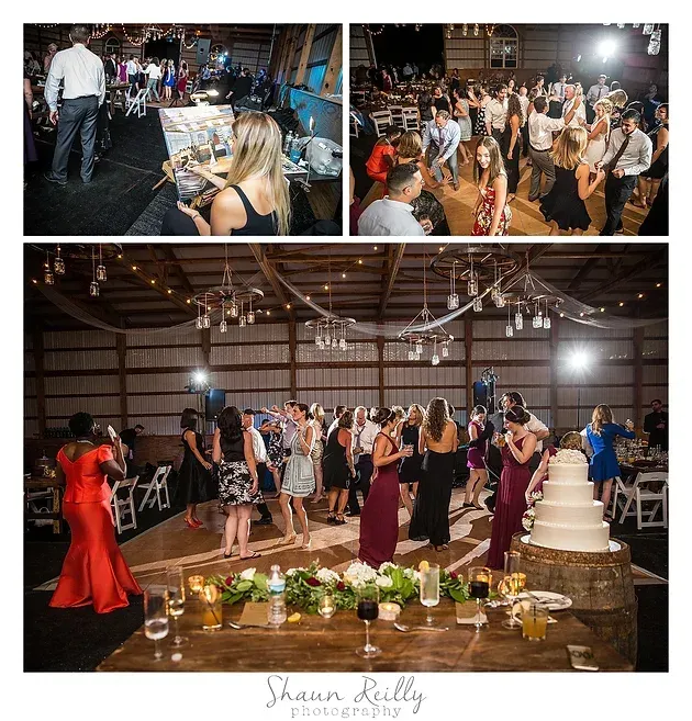 Guests dance at a wedding reception with a white tiered cake and a decorated dessert table nearby