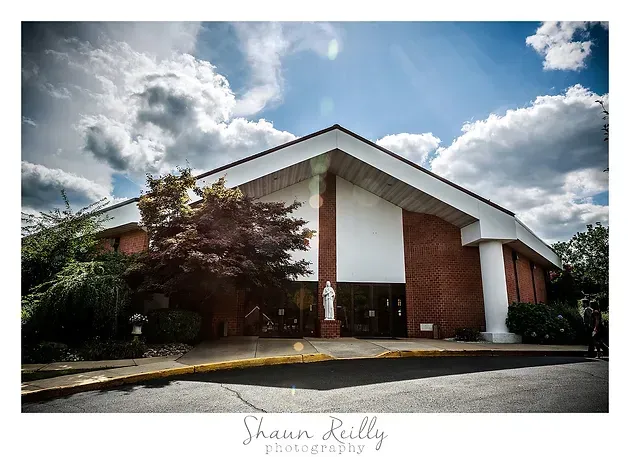 Modern church building with red brick columns under a cloudy sky
