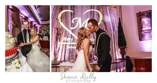 Bride and groom kiss at a pink-lit wedding reception beside a cake and heart-shaped light