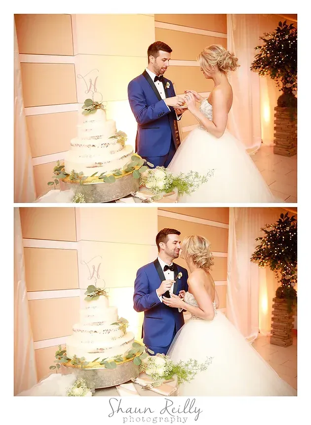 Bride and groom beside a multi-tiered wedding cake, smiling in a soft peach reception room