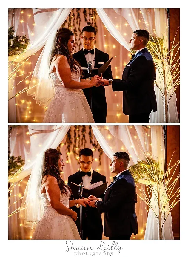 Wedding couple exchanging rings during an outdoor evening ceremony under white drapery and warm string lights