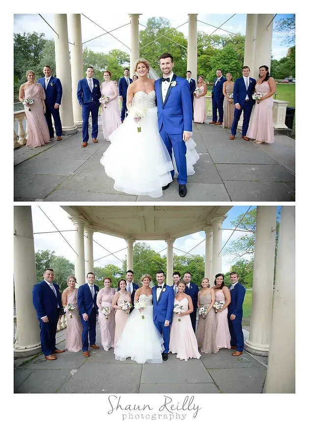 Wedding couple and bridal party posing in a pavilion, with the bride in white and groom in blue.