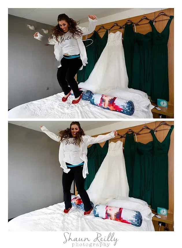 Woman jumping on a bed in a white room with green curtains and colorful pillows