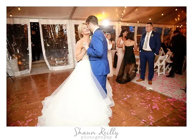 Bride and groom dancing at a wedding reception while guests watch and applaud