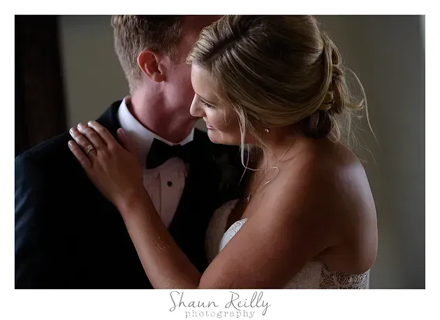 Couple in formal attire embracing closely during a romantic indoor portrait