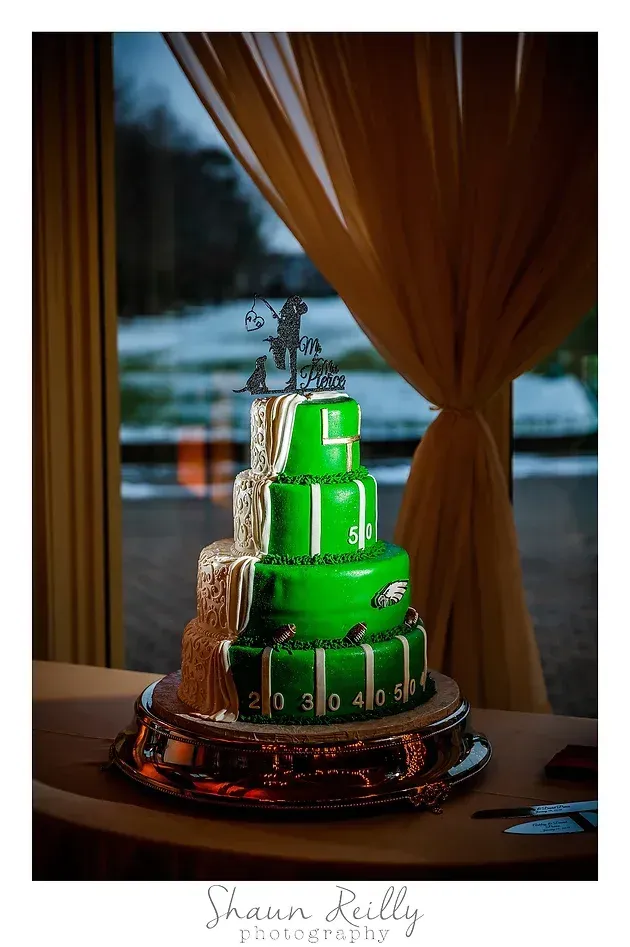 Green tiered cake on a silver stand beside a window with draped curtains and a snowy view
