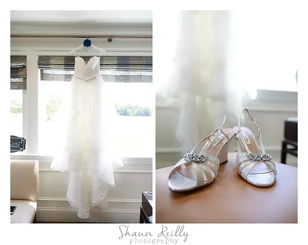 White wedding dress hanging by a window beside satin bridal shoes on a windowsill