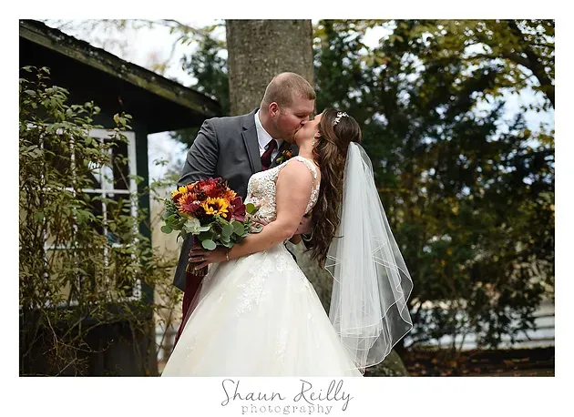 Bride and groom kissing outdoors, bride holding a colorful bouquet.