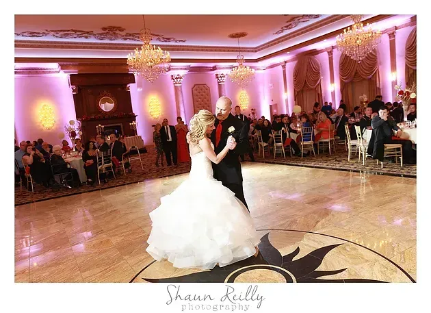 Bride and groom dancing in a pink-lit ballroom during a wedding reception