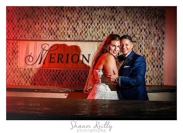 Bride and groom posing in front of a Merion sign at a wedding venue