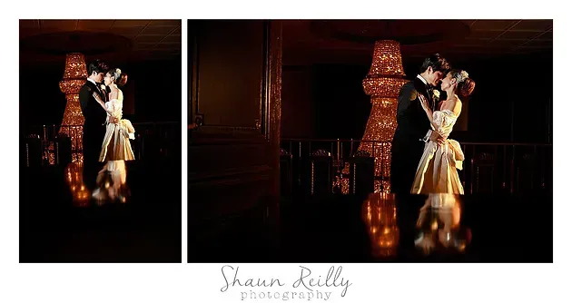 Couple in formal attire posing beside a stone column in a dim, warm-lit room