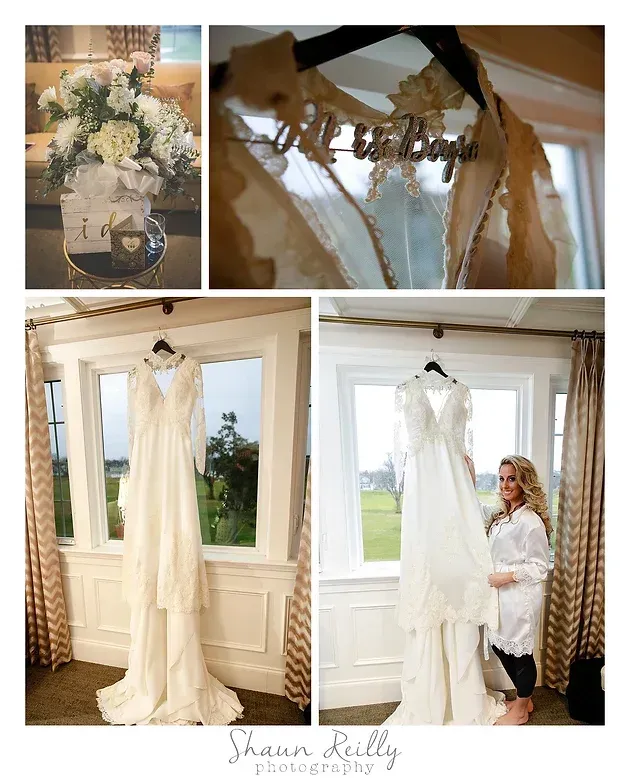 Wedding dress displayed by a window with white floral decor and a bride standing beside it