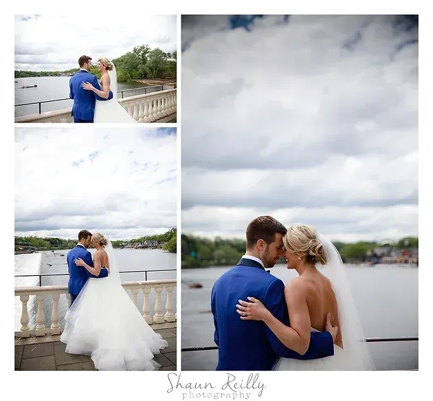 Bride and groom in blue on a waterfront balcony, embracing in wedding portraits beneath a cloudy sky