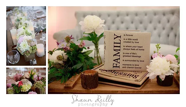 Floral memorial display with white and pink flowers, family sign, and candles on a wooden table