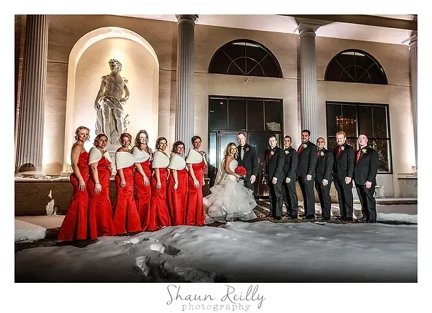 Wedding party in red and black standing outside a lit building at night