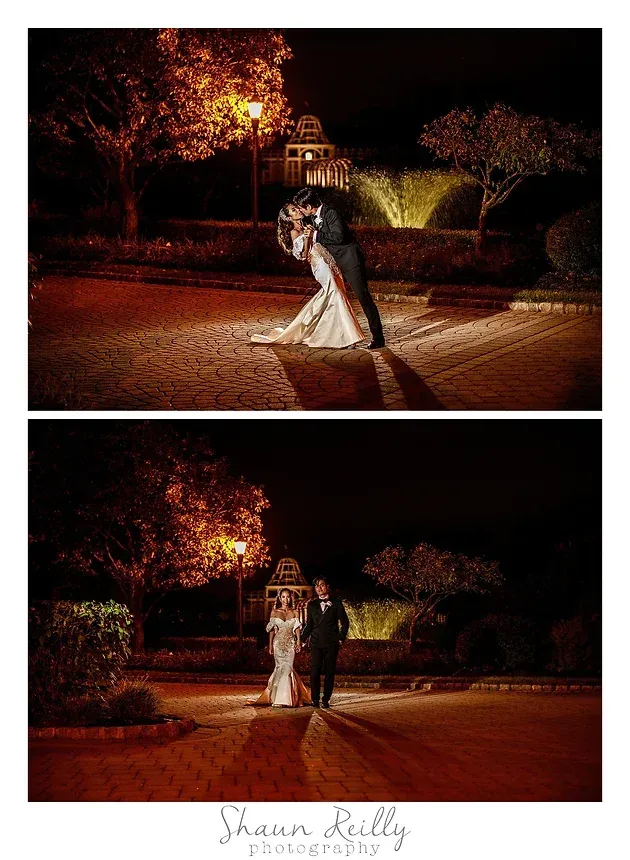 Couple in formal attire posing outdoors at night on a lit brick path, surrounded by trees and warm lights