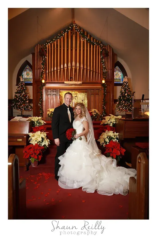 Bride and groom posing in a church before a decorated altar and organ pipes