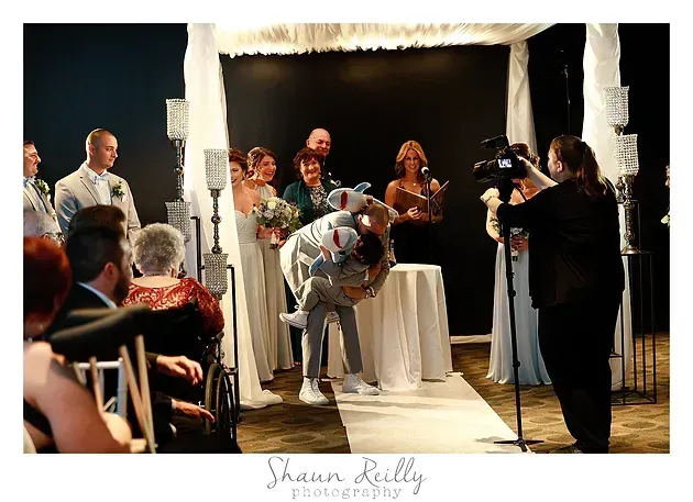 Wedding ceremony with officiant, bride and groom, and guests under a white canopy