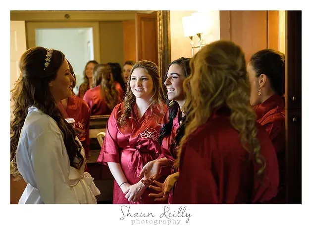 Women in red and white robes chatting indoors in a warmly lit room